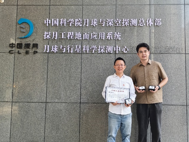 張小平教授（左一）與博士生赵斯哲（右一）領取嫦娥五號、六號月壤返回樣品